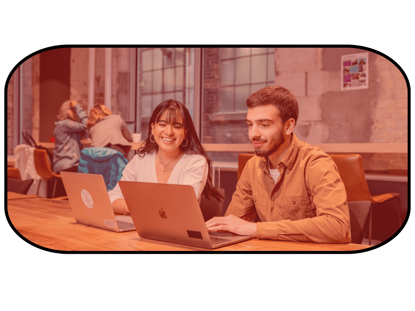 Two smiling students with laptops looking at the schedule.